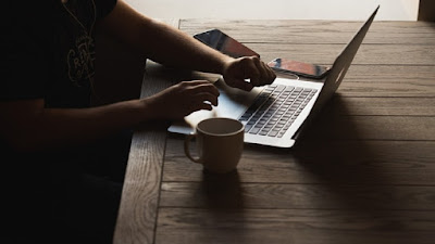 Lone worker in home business work station with a computer, mobile phone and a mug of beverage.