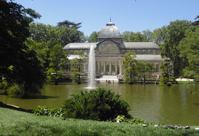 El Palacio de Cristal, con el lago delante, en el centro surtidor de agua y rodeado de vegetación