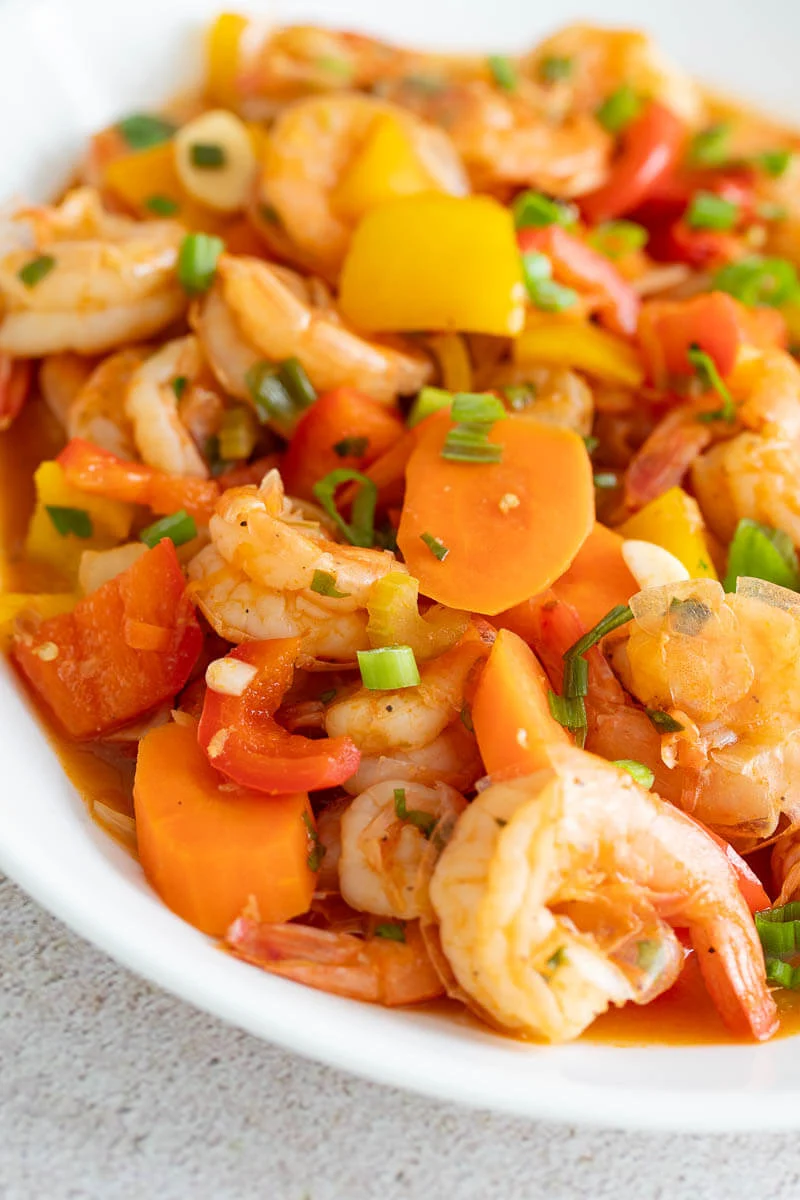 A close up of the pepper shrimp garnished with cilantro on a white plate.