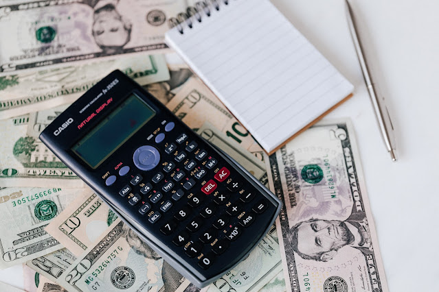 calculator and note pad placed on USA dollar stack