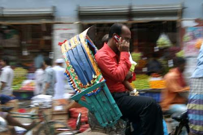 image of a rickshaw passenger talking on his cellular phone