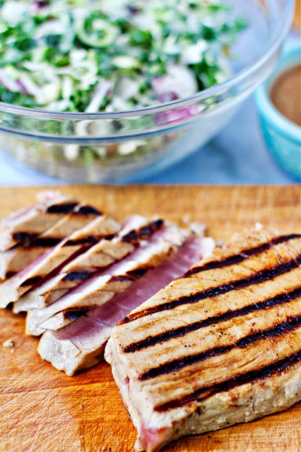 Grilled Tuna Steaks with Honey Vinaigrette sliced on a cutting board.