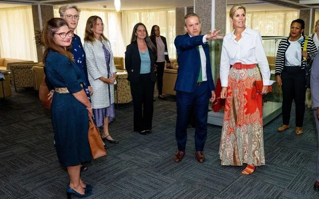 Queen Maxima wore a multicolor paisley print skirt by Etro. White silk shirt. Orange coral earrings and red leather pumps and clutch