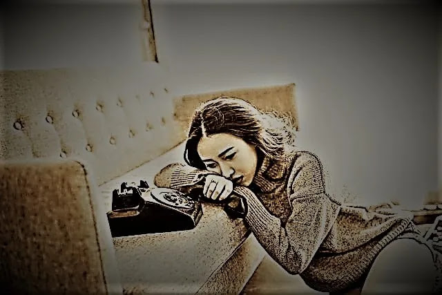A very sad alone girl lying around the sofa with a telephone.