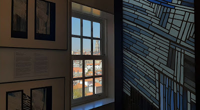 paines de vitral expostos junto à uma janela com vista para o Porto