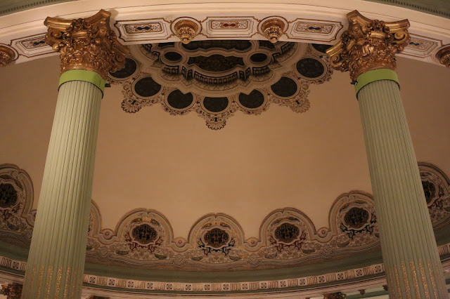 Columnas que sostienen una gran cúpula interior pintada y decorada de edificio antiguo.