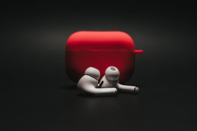 earbuds case in red with earbuds in front on a black background.