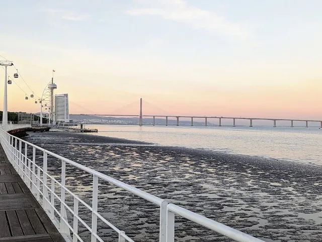 Sunset over the Vasco de Gama Bridge in Lisbon views from a walking path with a while railing in Expo