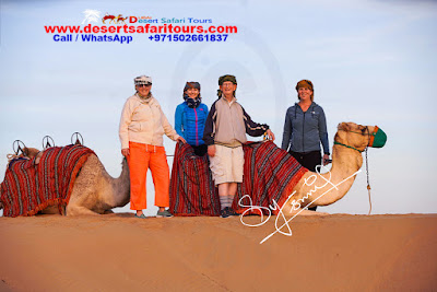 after camel trekking four people taking picture with camels