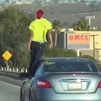 Lelaki menunjukkan aksi berbahaya berdiri atas tingkap kereta yang bergerak