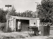The image of a sole shopkeeper tending his roadside stand at 1st Street and . (fairview)