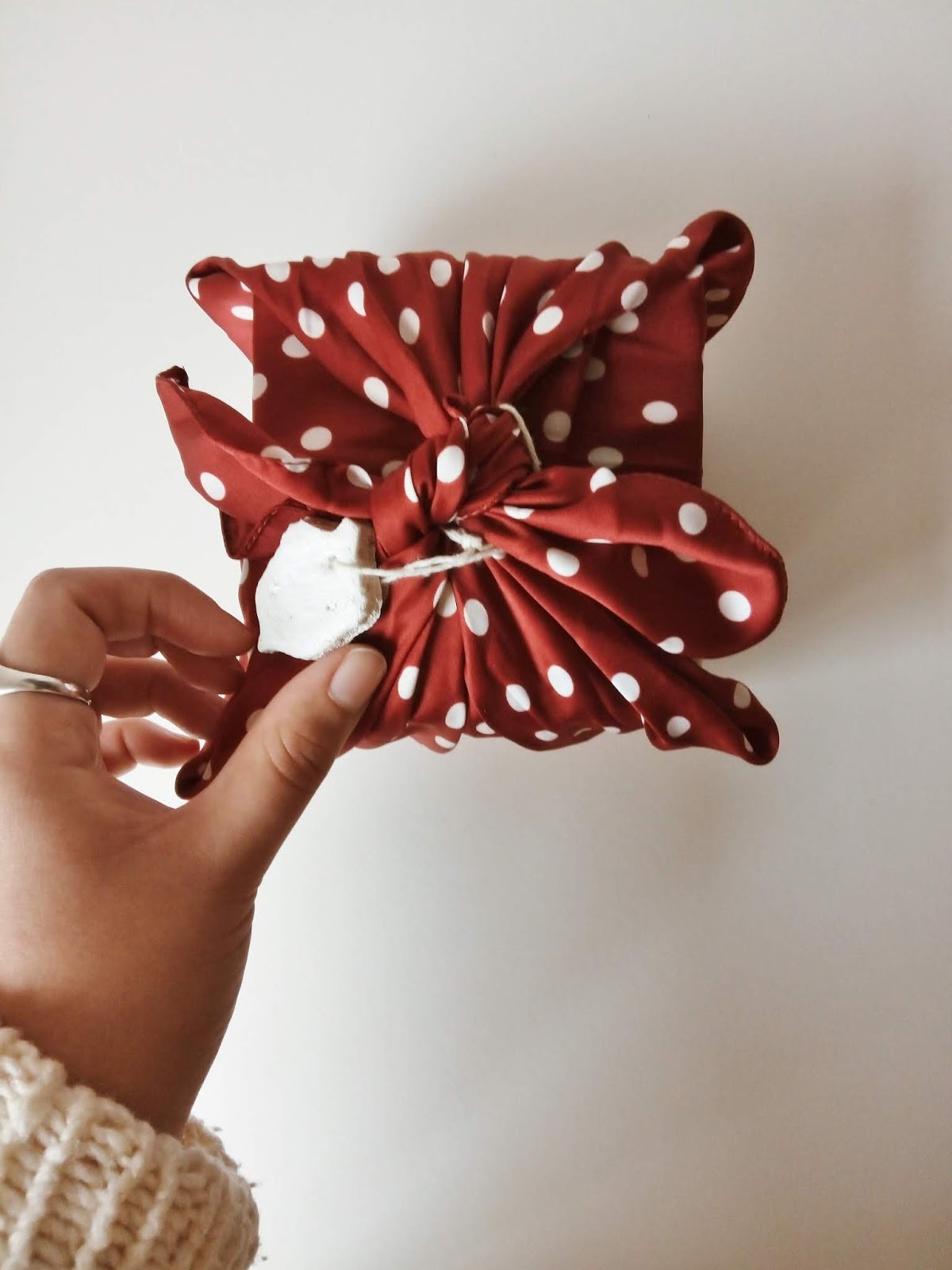 hand holding acorn-shaped gift tag on a red and white polka dot scarf