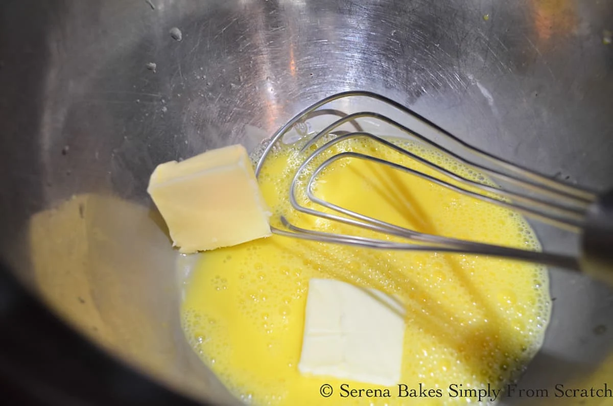 Butter being whiskey into egg yolk mixture in the top of a double boiler.