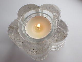 A clear resin flower shaped candle holder containing ashes