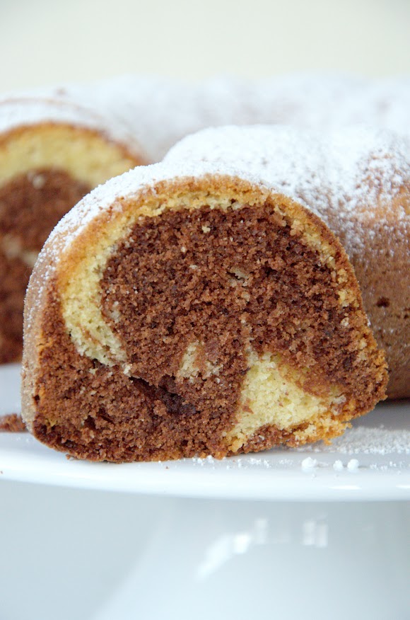 Aufgeschnittener Marmorgugelhupf auf weißer Kuchenplatte. Die Marmorierung ist schön zu sehen.