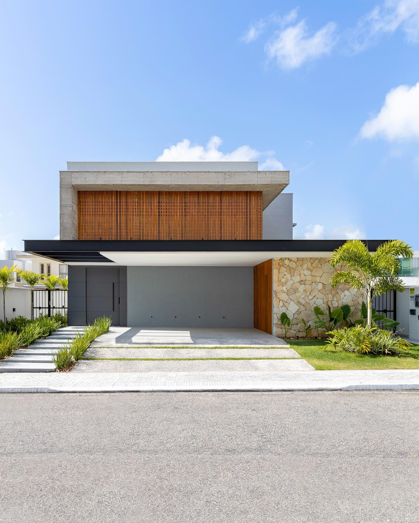 Fachada de casa contemporânea com pedra ferro e madeira + muro de