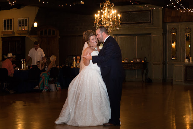  Cassie and Wyatt tied the knot at The Palace Event Center, in Yukon, OK, on July 15, 2017.   The venue’s magnificent wood entry doorways, outside rock façade, and adjacent country landscape provided the perfect backdrop to photograph the first look and pictures of the jovial wedding party.  The venue was spacious, which allowed us to sneak in a few pre-dressed shots of the girls in their “Wedding Tribe” t-shirts.     Cassie’s elegant, form-fitting, strapless, satin wedding dress overlaid with lace and sequins looked like it was made especially for her.  Wyatt was quite the Knight in Shining Armor dressed in his navy suit, grey vest, and burgundy tie.  The four beautiful bridesmaids wore matching full-length, flowing, burgundy gowns, slit at the knee.  Cassie’s gorgeous bouquet was composed of baby’s breath, peonies and ranunculus in rich hues of vibrant burgundy, red, pink, burnt orange, and yellow gold.  To add to the excitement of the day, their son had a special assignment—carrying the sign down the aisle that stated, “Daddy, Here Comes Our Girl.”     The venue’s grand ballroom, with it’s beautiful chandeliers and romantic lighting, was the perfect backdrop for the couple’s reception.  Candlelight, flowers, and twinkle lights adorned the nuptial stage, and after the vow exchange, Cassie and Wyatt participated in their first dance.  Guests were invited to enjoy the buffet, the cutting of the cake, and the toasts by the best man and bridesmaid.  Chairs were quickly removed from the dance floor, and while almost everyone spent the rest of the afternoon relaxing, dancing and socializing, there was a particularly fun-loving group of guests who decorated the bride and groom’s Jeep with sayings, crepe paper, and a car filled-to-the-brim with balloons!        Cassie stated that the best part of the wedding was being able to see so many family and friends at the reception having fun and enjoying themselves.  She said, “If we had it to do over, we wouldn’t do anything differently…it was perfect for both of us!”     It was a pleasure to capture the special moments of this memorable wedding day for Cassie and Wyatt, and we wish them a lifetime of love and happiness. 