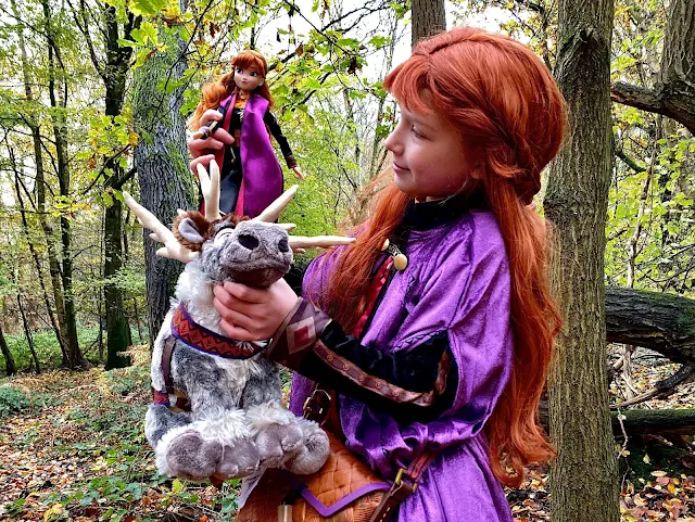 A girl dressed as Anna playing with the singing Anna doll and soft Sven reindeer toy from shopDisney
