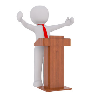 A stylised figure stands behind a lectern, wearing a tie, arms outstretched.