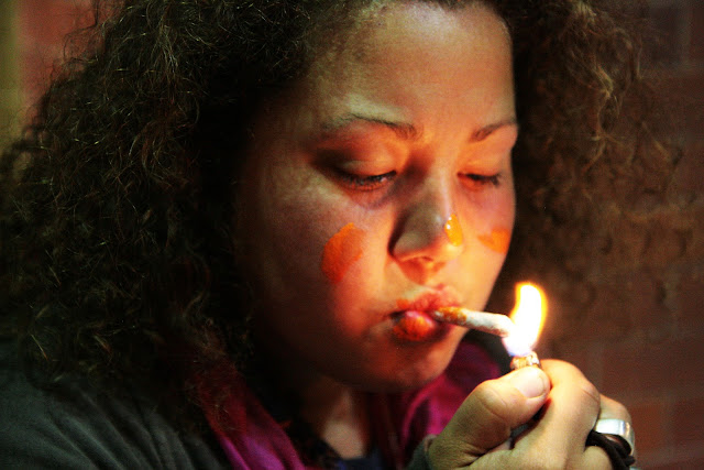 A girl getting ready to smoke pot as she lights a joint on the street in San Francisco, California.