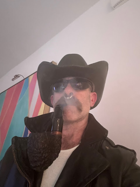 Cowboy wearing black leather jacket with a huge pipe in mouth sunglasses on face
