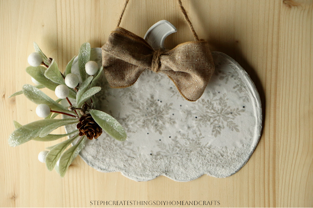 Close up of metal pumpkin with snowflake design with holiday foliage and bow being displayed