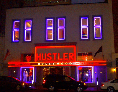 This a photo of white building.  The windows are traced by purple neon lights. The Marque is in red Neon.  The word Hollywood is in white letter. 