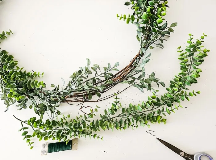 adding two types of greenery to wreath