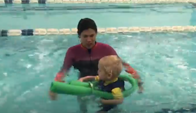 Picture of a swim teacher and her Cerebral Palsy student who is swimming with a noodle - bolster wrapped around him