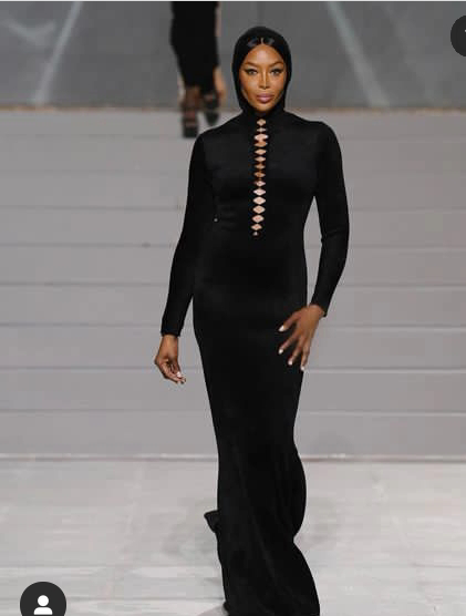 Naomi Campbell Flaunts Her Curves In A Black Long Sleeve Neck Dress At A Fashion Event