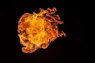 An orange flame with no visible source, set against an entirely black background.