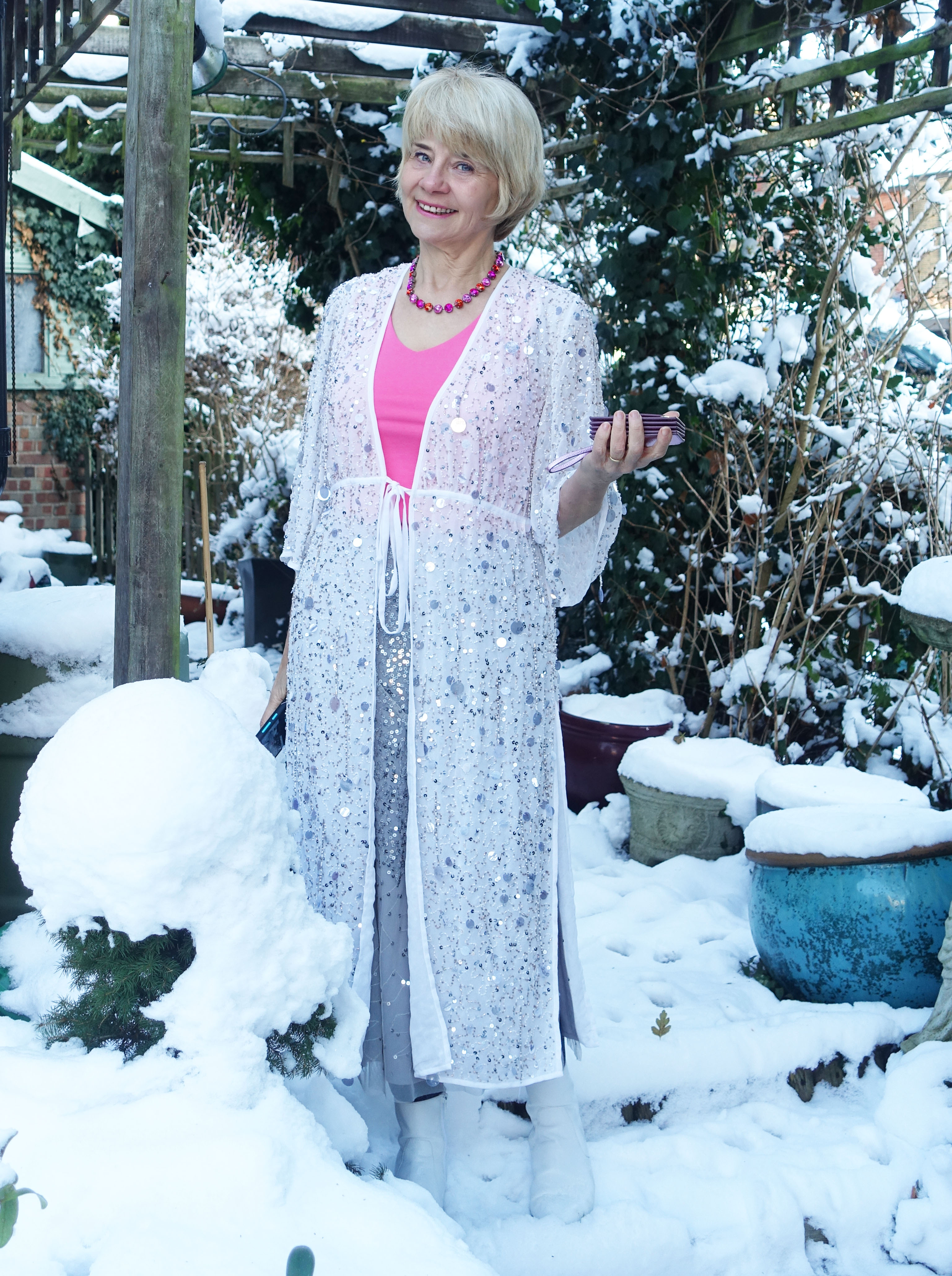 A white embellished duster coat and silver sequin skirt create a sparkly outfit for Is This Mutton blogger Gail Hanlon