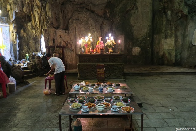 Attendant preparing offerings for prayer session inside Huyen Khong Cave