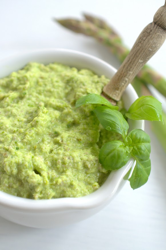 Grünes Spargelpesto ist in einer weißen Schüssel angerichtet und mit Basilikumblättern garniert.