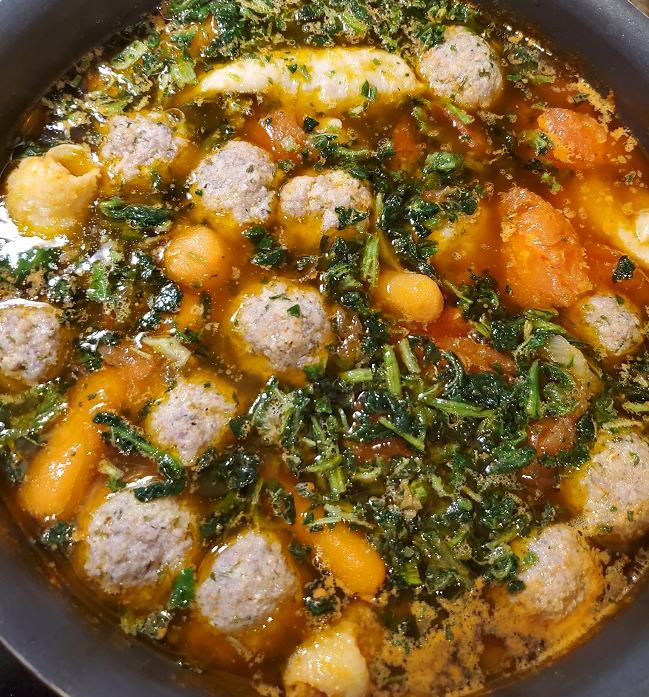 this is a soup pan full of tortellini, escarole and meatballs