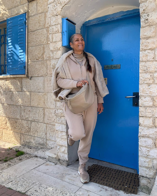 woman in beige jogging suit against a blue door