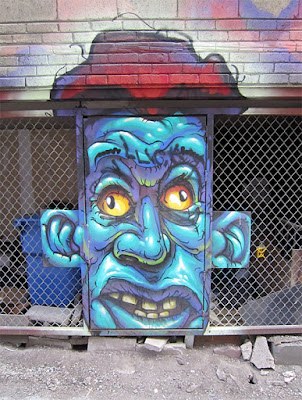 Photo of a face painted on a door in alley