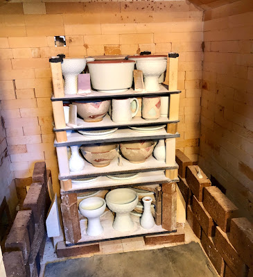 The back of the kiln is loaded with a variety of heights of pottery