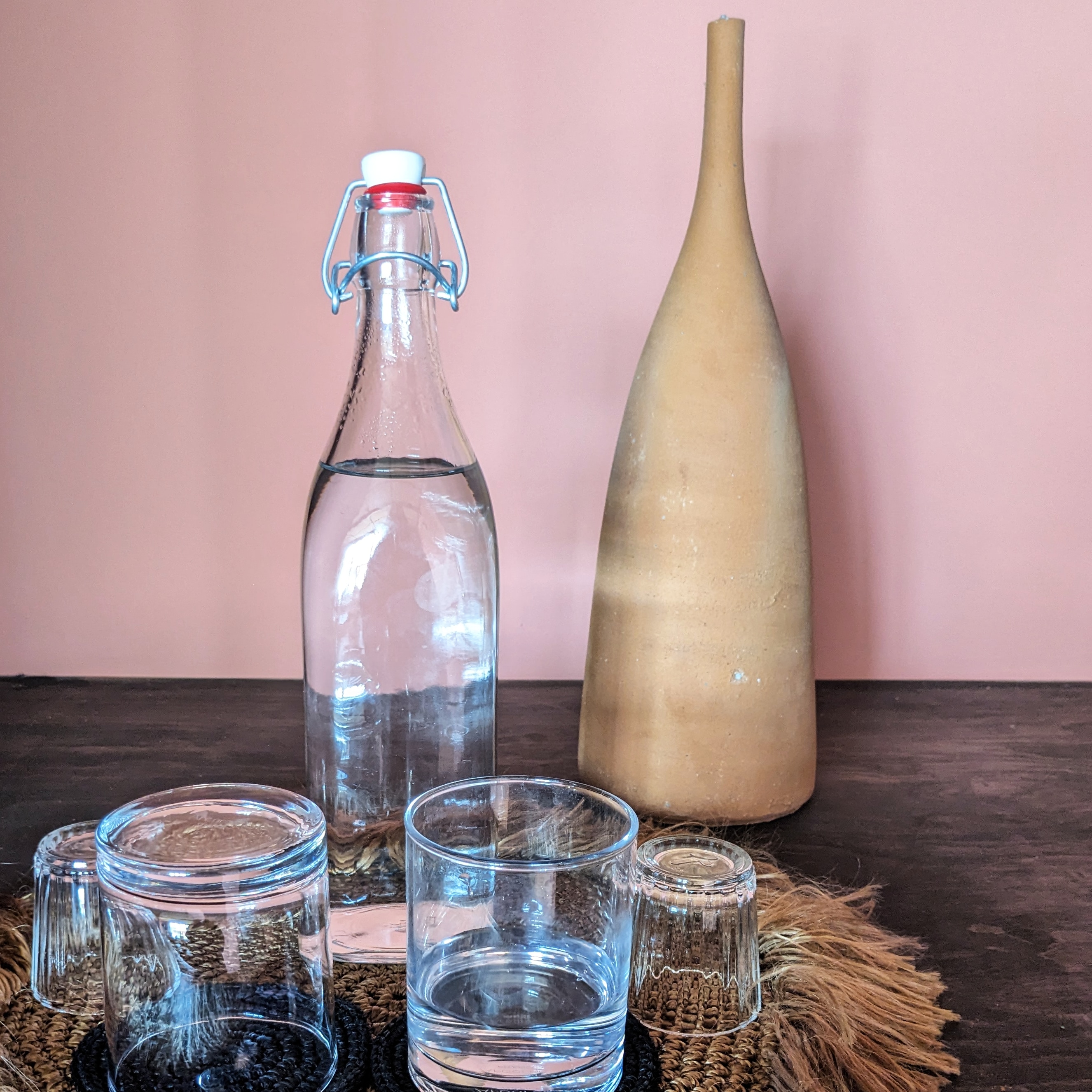 a water filled glass bottle and two glasses against a pink room in a bedroom at Our Habitas hotel in Mexico's San Miguel de Allende