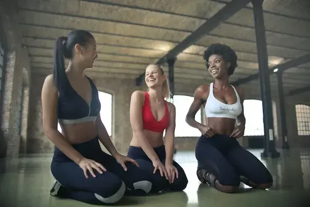 Three Young Girls Resting and Discussing in a Gym