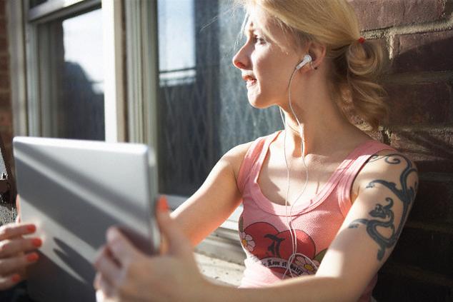 A young girl under the sun shines has a black dragon tattoo on her arm.