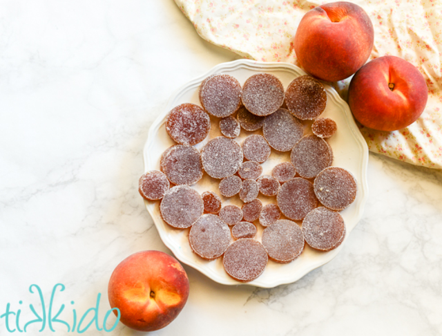 Peach candied jellies on a white place with fresh peaches on the table