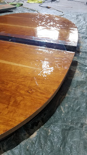 A photograph of a portion of a refinished table, with a lumpy and unevenly poured resin finish.