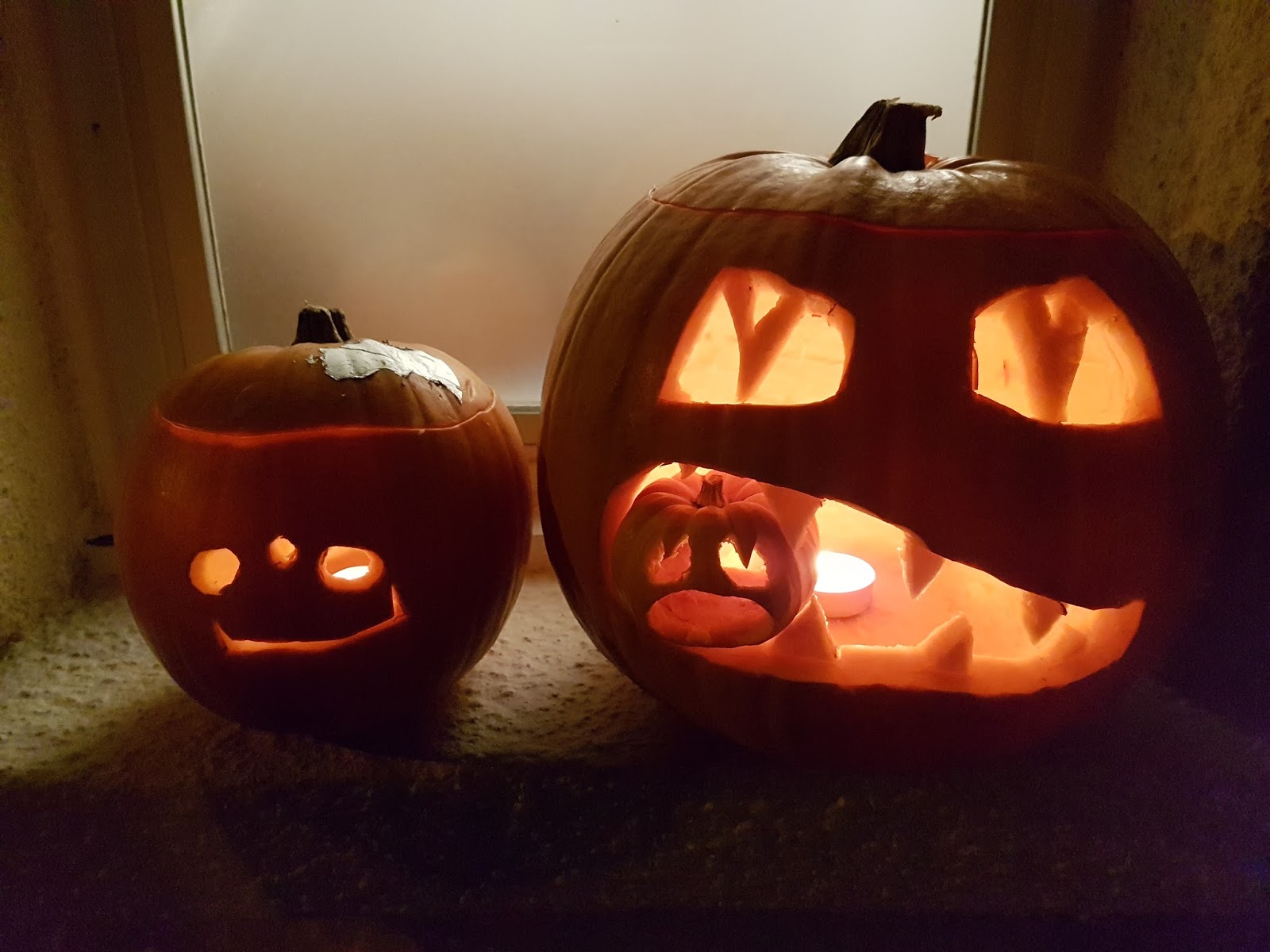 two jack o lanterns with one eating a mini pumpkin and one made by a toddler