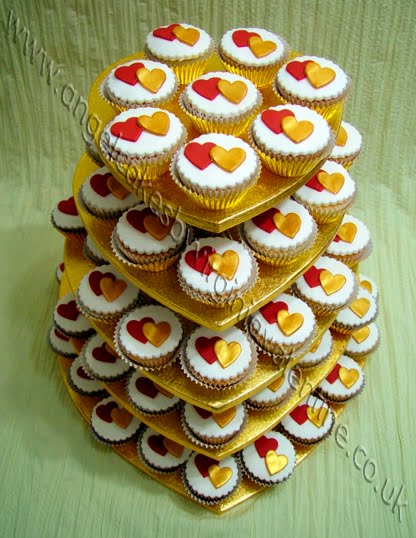 Heartshaped cupcake stand full of white cupcakes with gold and red hearts