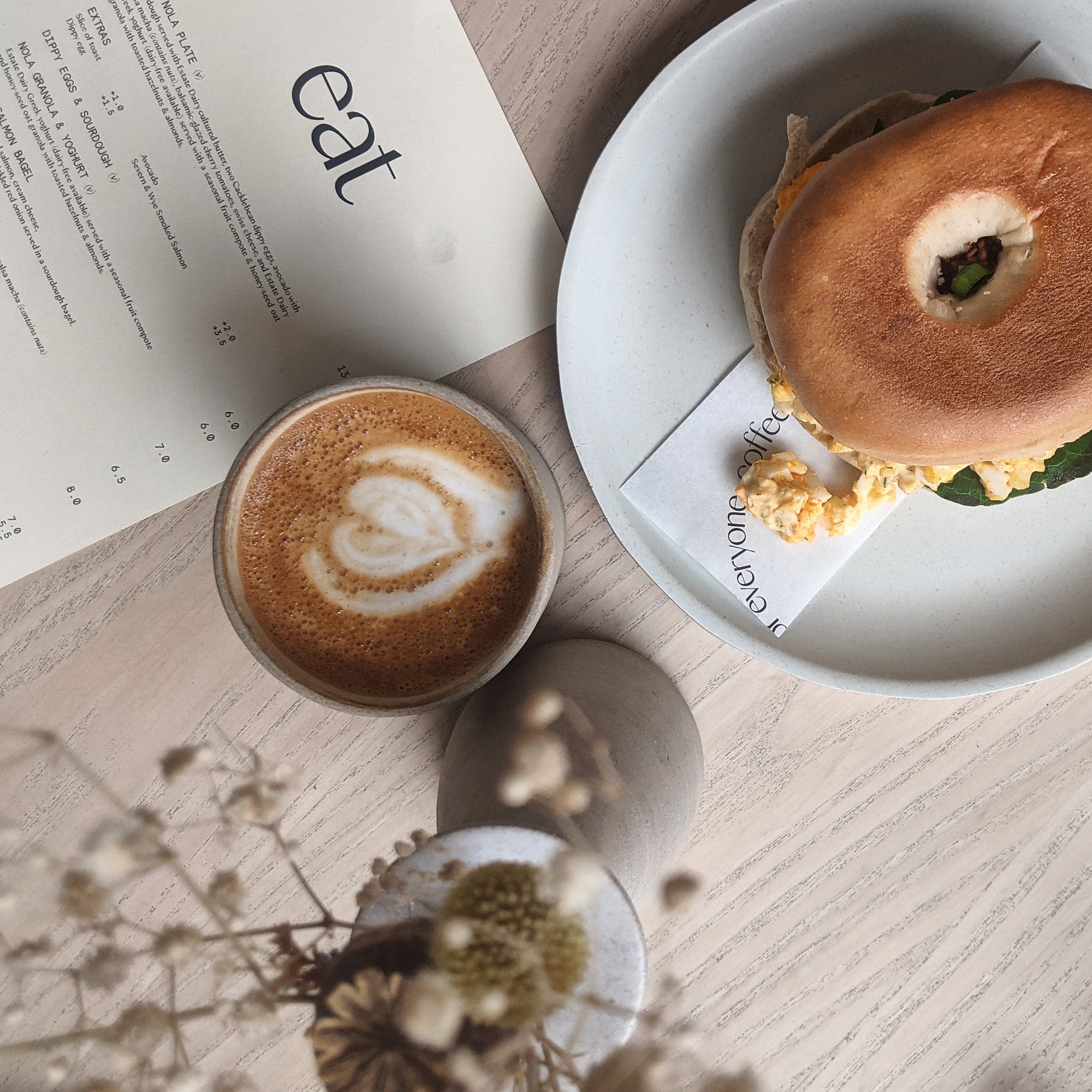 A filled bagel next to a flat white at Nola in Peckham, one of the best places to get a unique breakfast in london