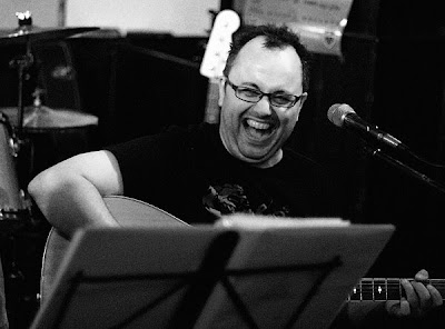 Seated guitarist laughing and smiling, Toronto portrait photographer Robert Rafton