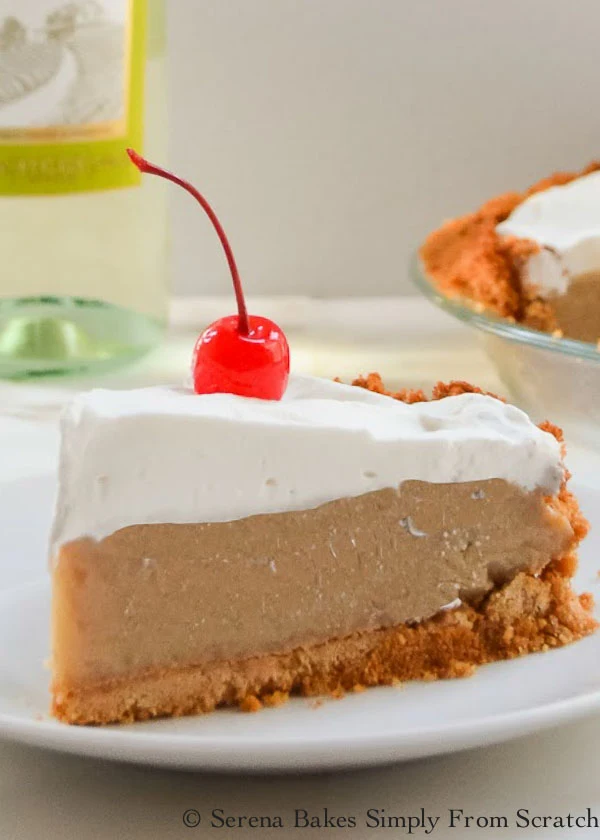 A slice Frozen Root Beer Float Pie covered with sweetened whipped cream topped with a cherry.