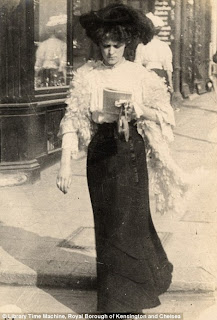 Edwardian Street Fashion depicts a woman reading as she walks down the street.