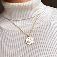 Gold Celestial Space Pendant Necklace by Constellation Co UK, with Saturn, crescent moon and stars, worn on a white roll neck jumper.